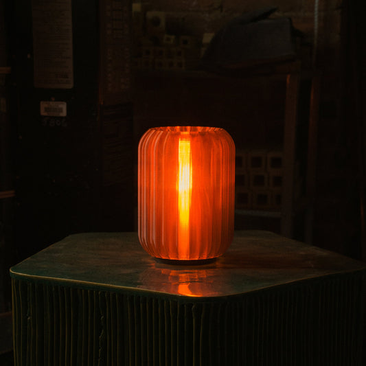 Mini Allium Lamp providing warm ambient light on a green table, showcasing its cordless design and sculptural elegance.