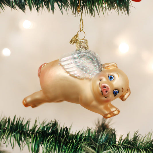 Flying Pig Glass Ornament hanging on a Christmas tree, handcrafted artisan decor for magical celebrations.