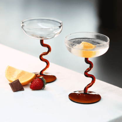 Amber Swirl Cocktail Glass Set with artisan design, showcasing handcrafted glasses beside lemon and strawberry.