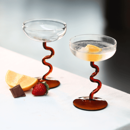 Amber Swirl Cocktail Glass Set with artisan design, showcasing handcrafted glasses beside lemon and strawberry.