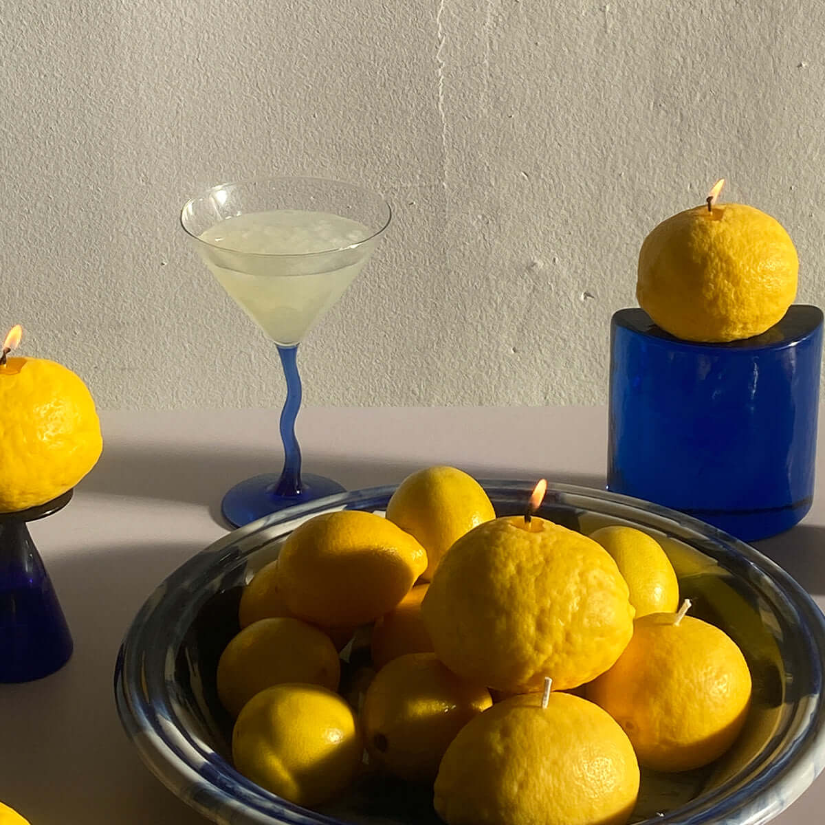 Large Lemon Candle surrounded by fresh lemons and a stylish cocktail, perfect artisan decor for any handmade ambiance.
