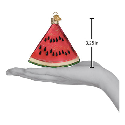Hand holding a Watermelon Wedge Ornament, a handcrafted artisan decor piece measuring 3.25 inches.