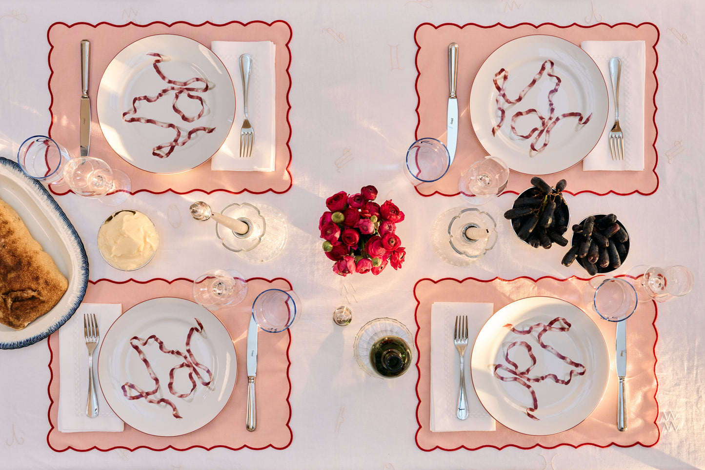 Dining table set with plates, cutlery, and decorative items on a white tablecloth.