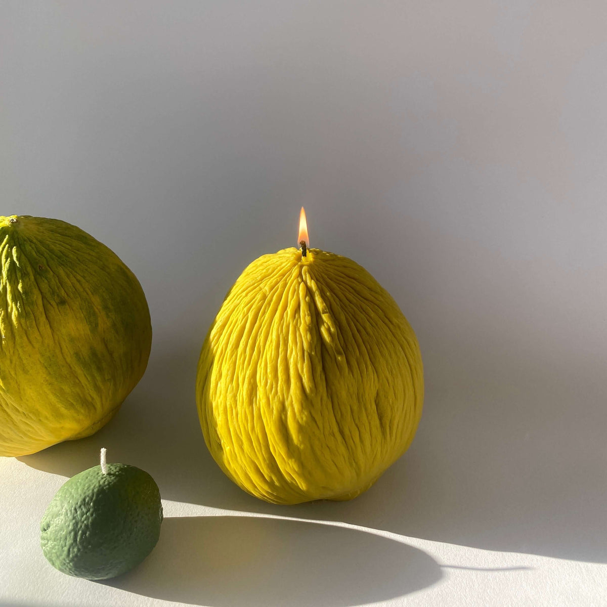 Casaba Melon Candle glowing with a warm flame, surrounded by artisan decor, showcasing handmade craftsmanship.