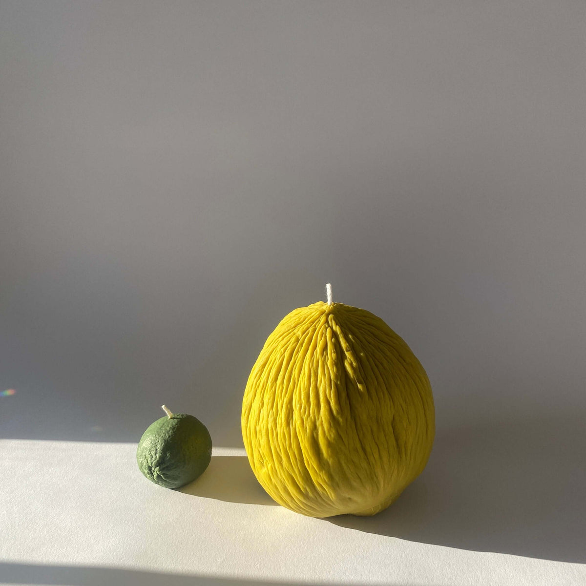 Casaba Melon Candle and smaller green candle, handcrafted artisan decor for a fruity atmosphere.