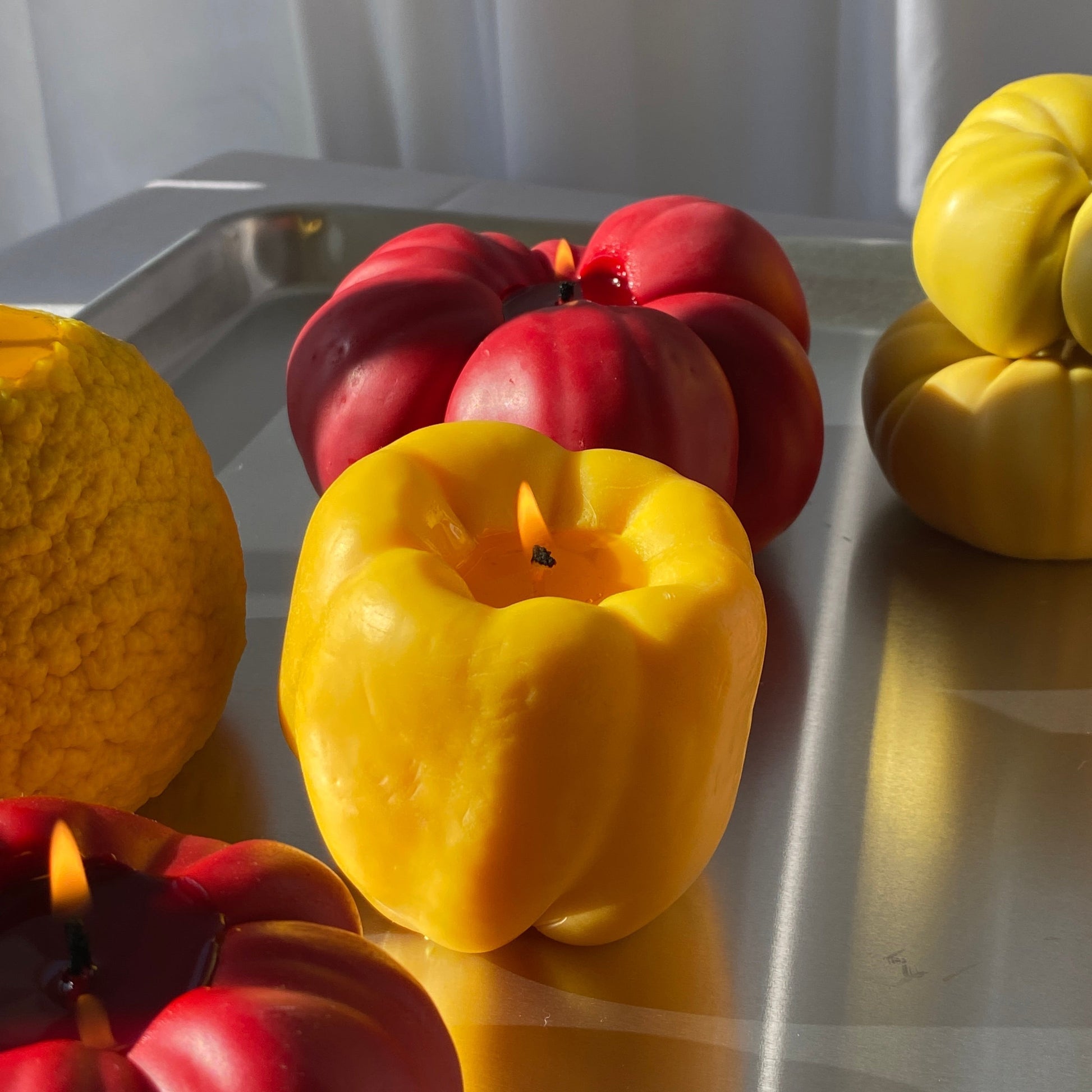 Bell Pepper Candle - Yellow surrounded by colorful artisan candles on a stylish tray for unique decor.