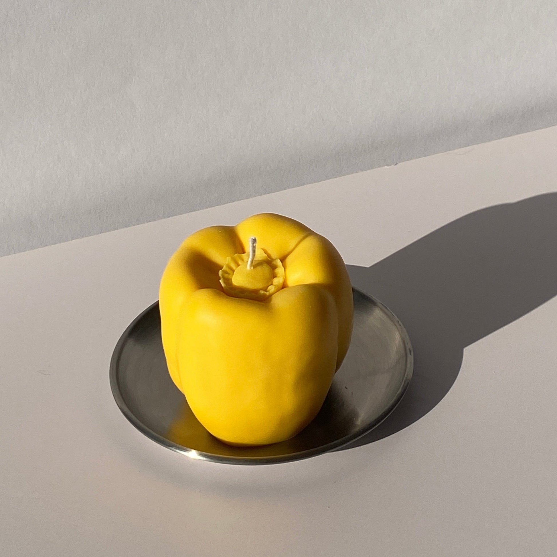 Bell Pepper Candle - Yellow on a metal plate, adding artisan decor with its handcrafted, handmade charm.