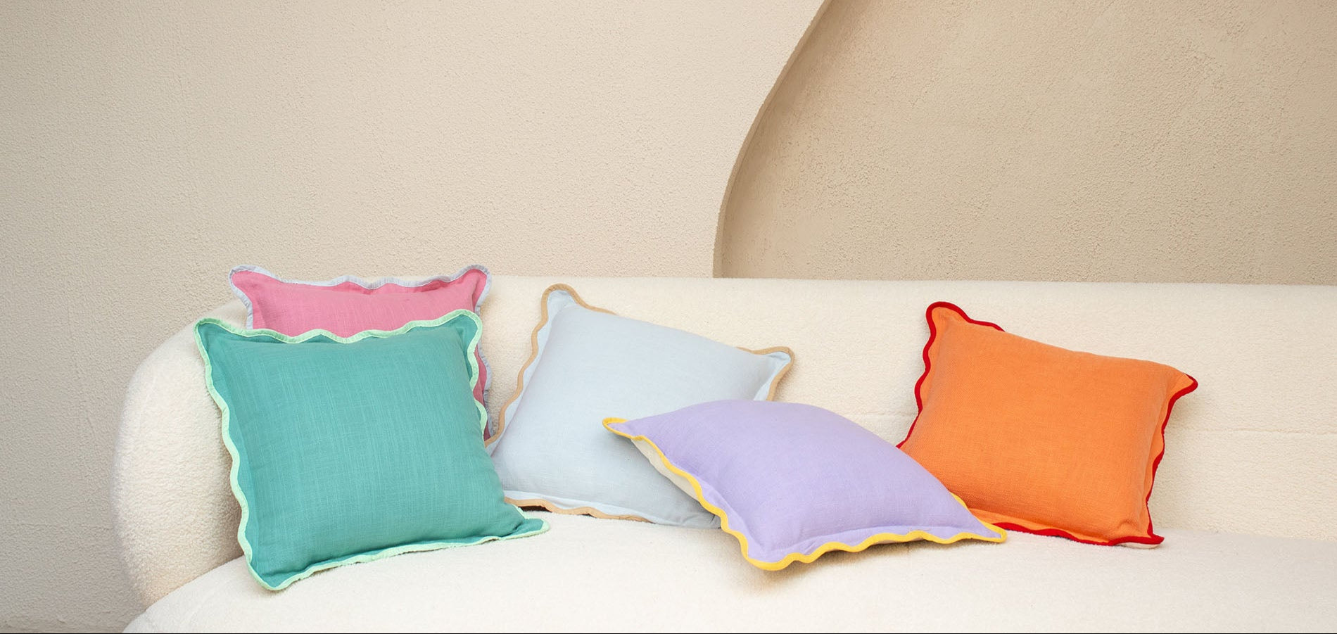 Colorful pillows on a white sofa against a beige wall