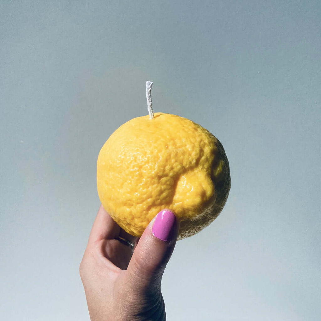 Hand holding a Large Lemon Candle, artisan handmade decor perfect for adding citrus vibes to any space.