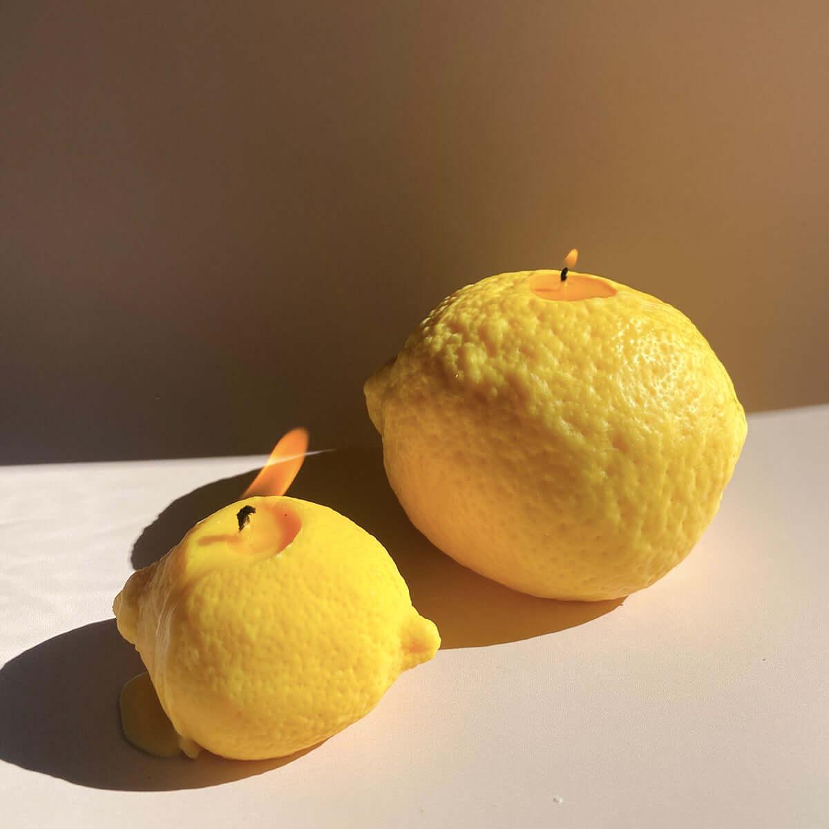 Large Lemon Candle - handcrafted artisan decor, featuring big and small lemon-shaped candles glowing brightly.
