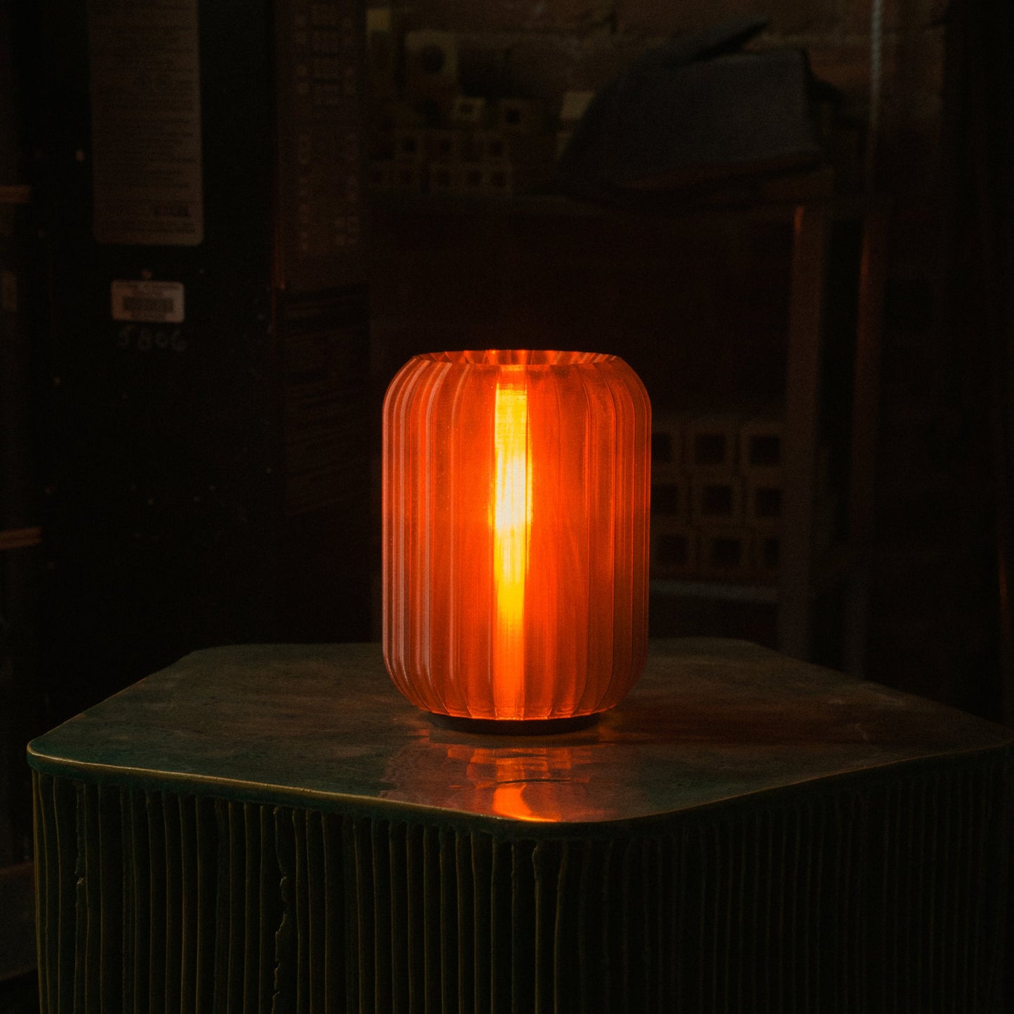 Mini Allium Lamp providing warm ambient light on a green table, showcasing its cordless design and sculptural elegance.