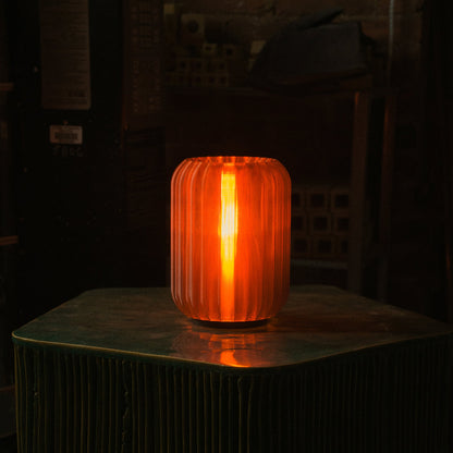 Mini Allium Lamp providing warm ambient light on a green table, showcasing its cordless design and sculptural elegance.