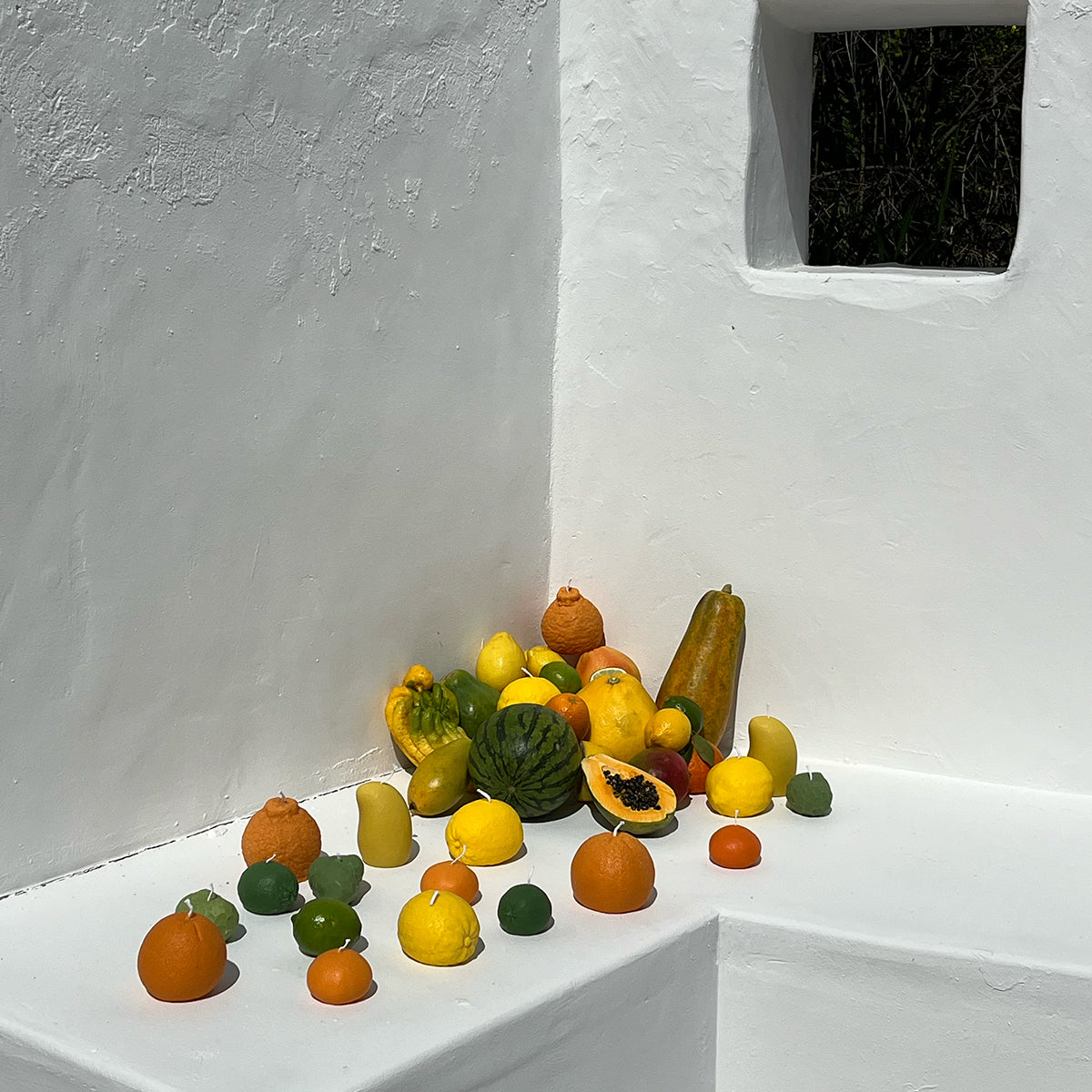 Colorful assortment of fruits displayed against a white wall, creating a vibrant and natural decor.