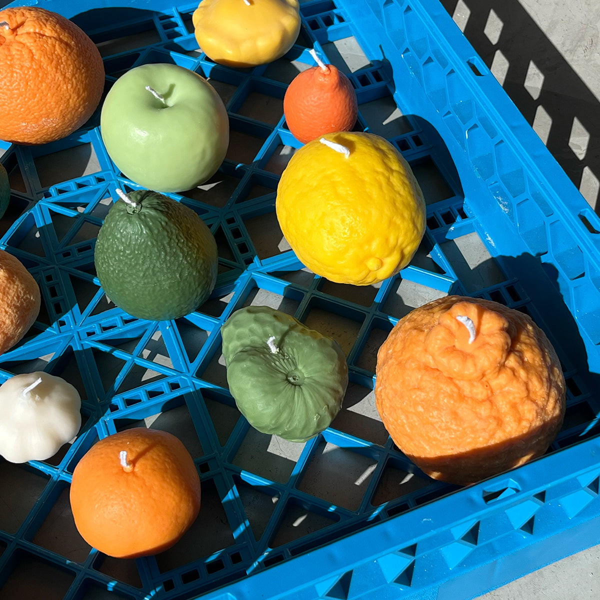 Colorful artisan Cherimoya Candles arranged in a blue crate, showcasing handcrafted home decor.