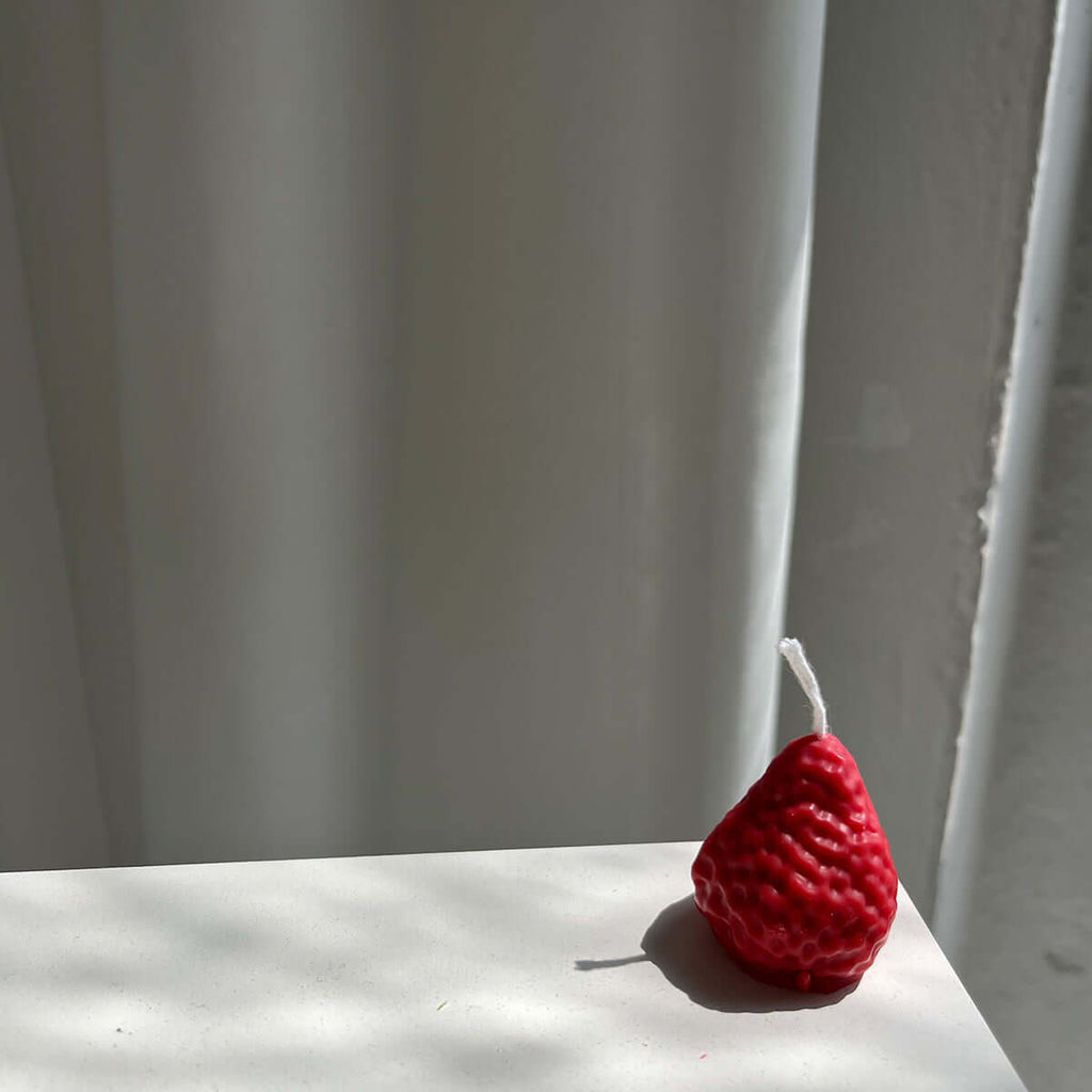 Strawberry Candles - 8 Pack, artisan handmade decor candle in the shape of a strawberry on a white surface.