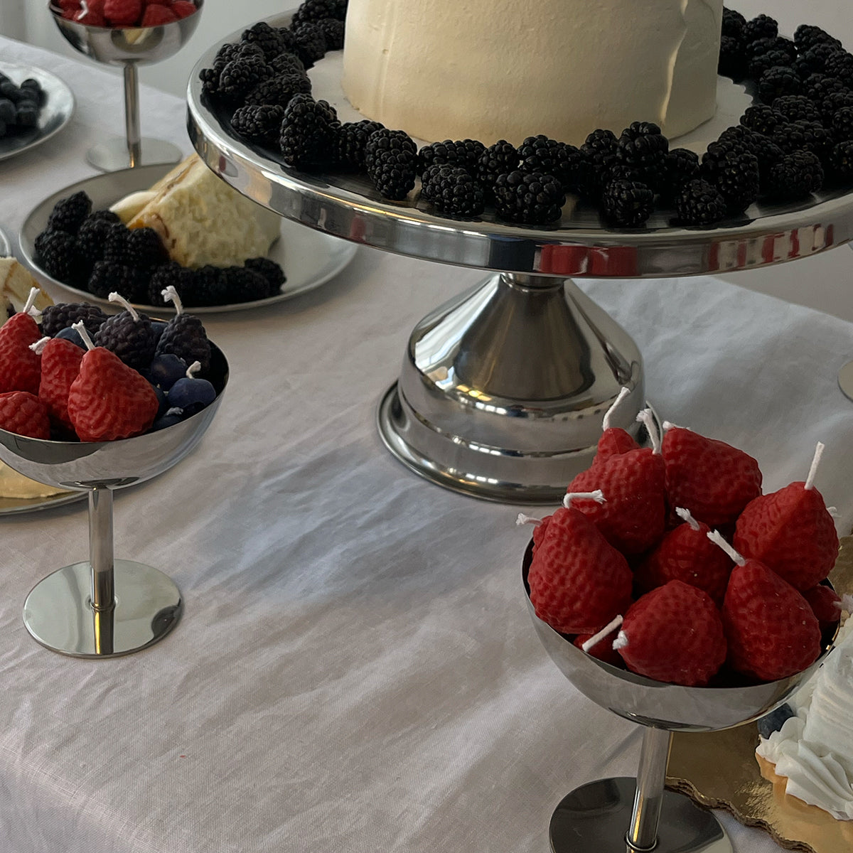 Strawberry Candles - 8 Pack displayed at a festive gathering with blackberries and cake.